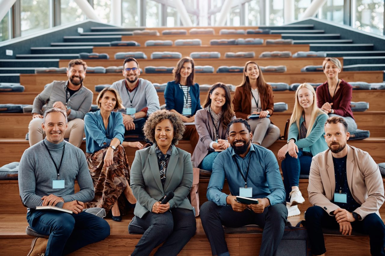 multiracial group of happy business seminar attendees at convention center looking at camera